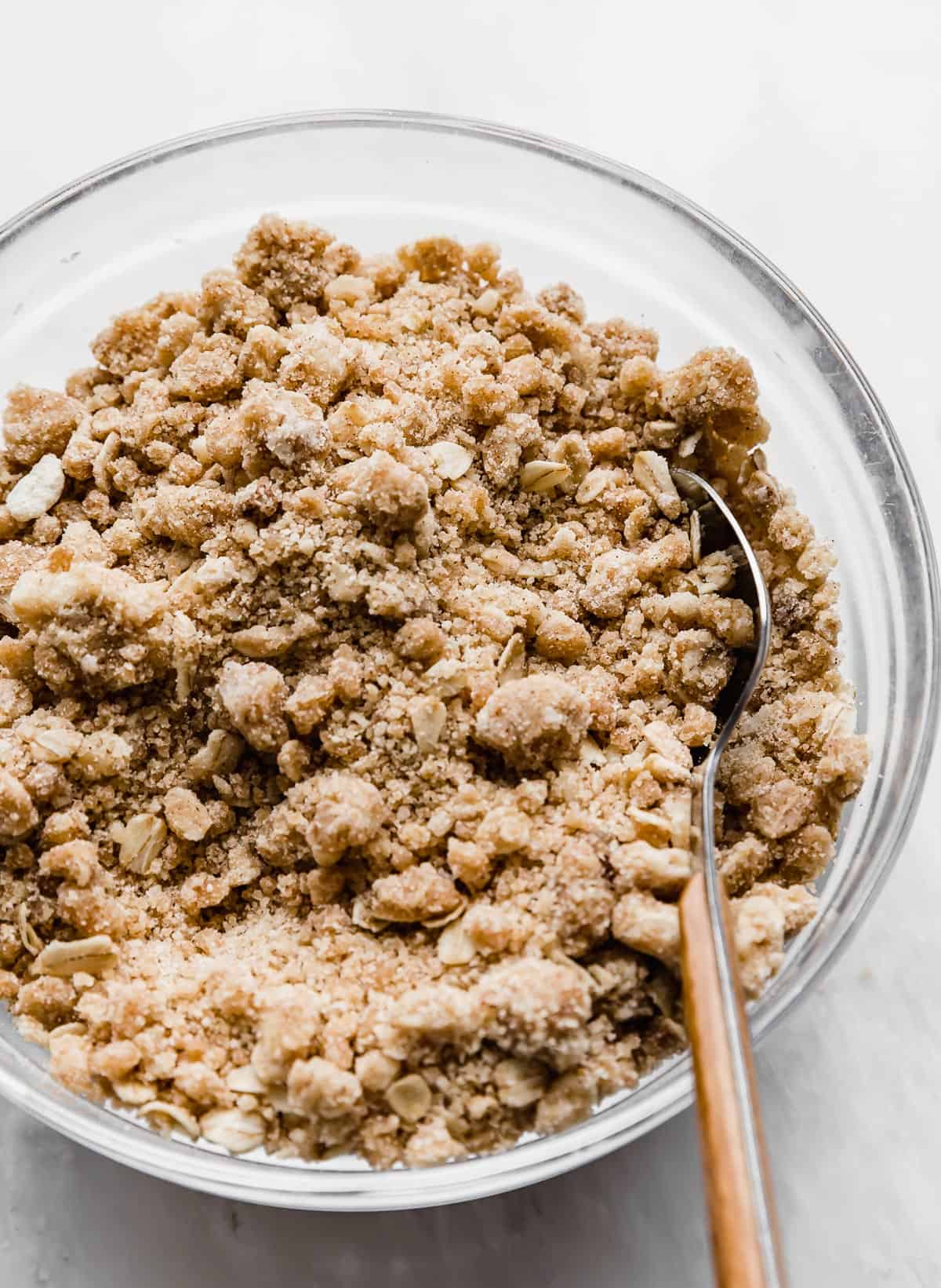 A close photo of Streusel Topping Recipe with oats, in a glass bowl on a white background.