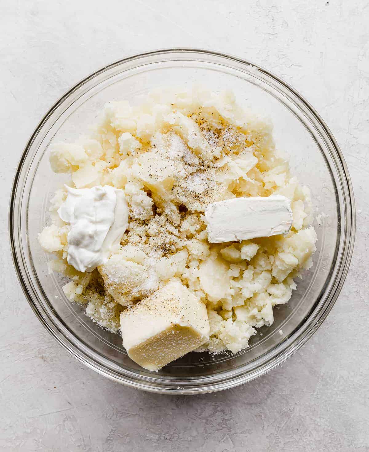 Potato pulp in a bowl with butter, cream cheese, and sour cream.