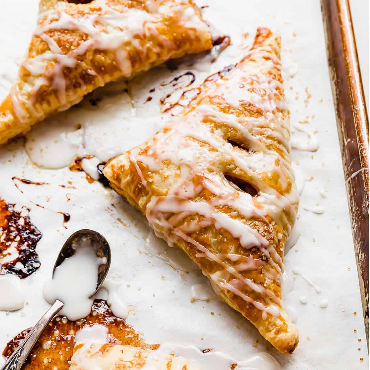 A glazed Puff Pastry Apple Turnover on a white parchment paper.