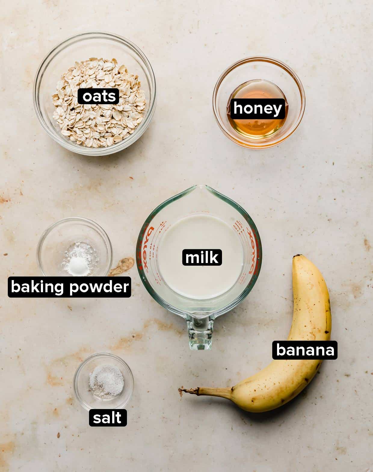 Ingredients used to make Baked Oats on a cream background.