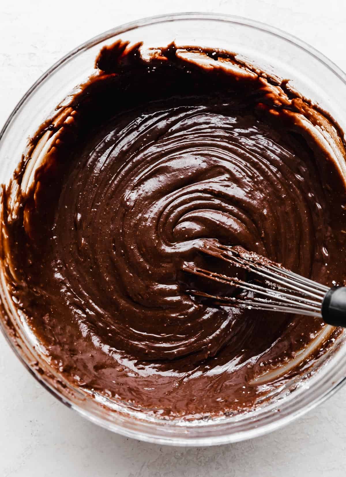 A thick chocolate Bundt Cake frosting in a glass bowl.