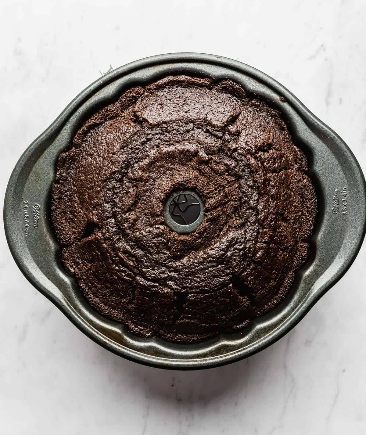 A baked chocolate Bundt Cake in a bundt pan on a white background.