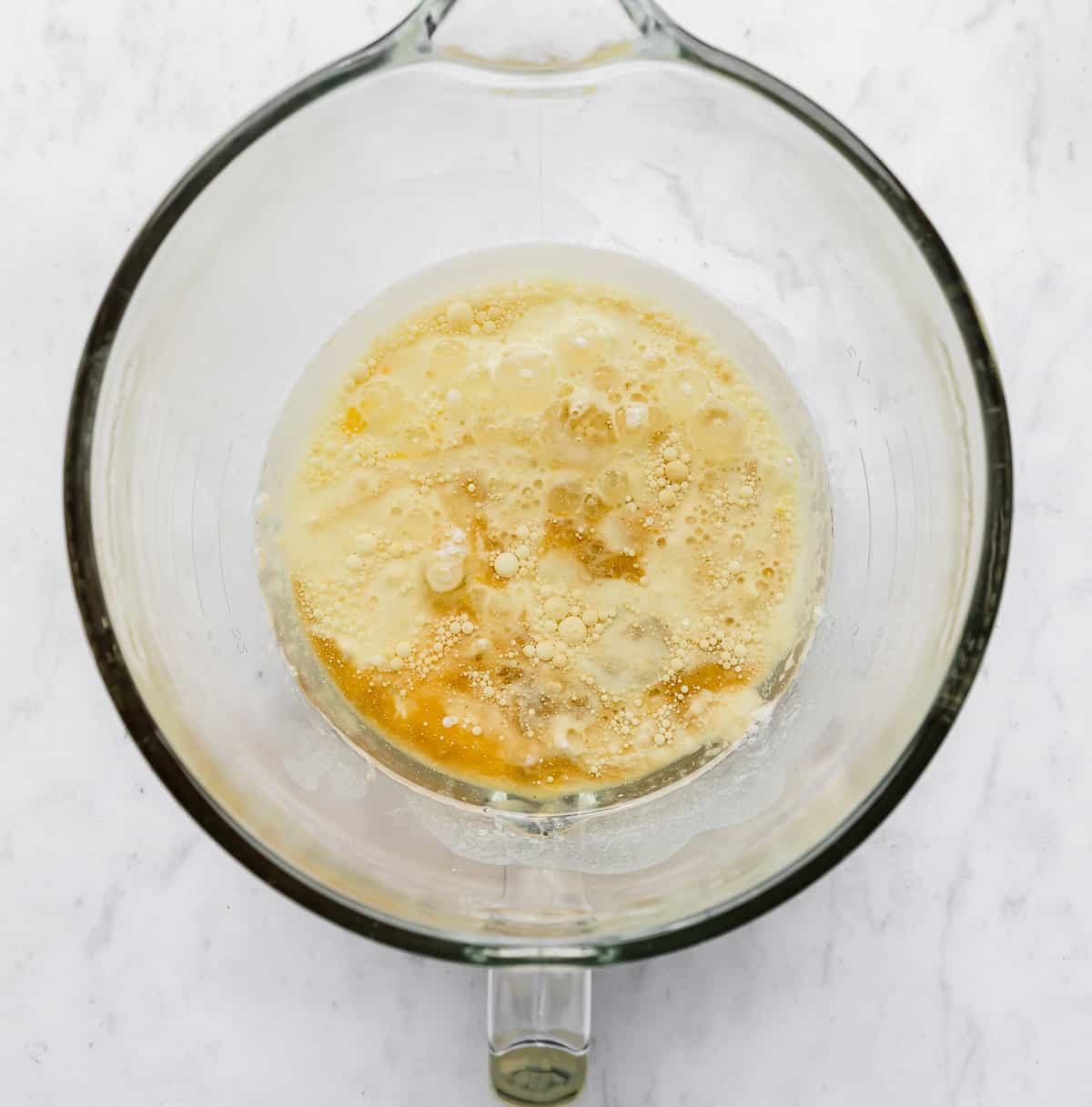 A glass mixing bowl with oil, eggs, buttermilk, and vanilla in it.