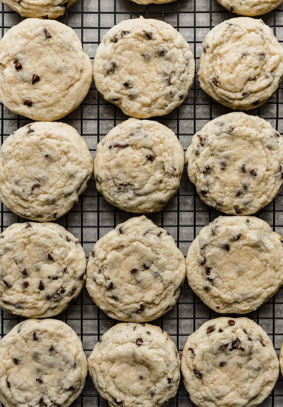 Sugar cookies with mini chocolate chips baked into them, on a black wire cooling rack.