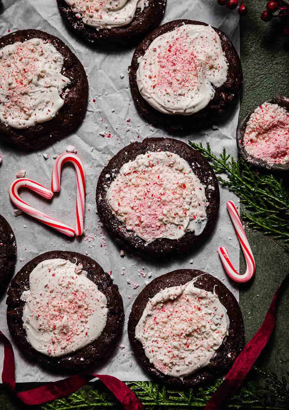 Overhead photos of chocolate Peppermint Bark Cookies topped with white chocolate and crushed candy canes, with faux pine needs around the border of the image.