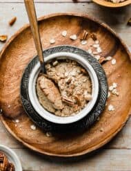 A ramekin with Baked Oats in it on a round wooden plate.