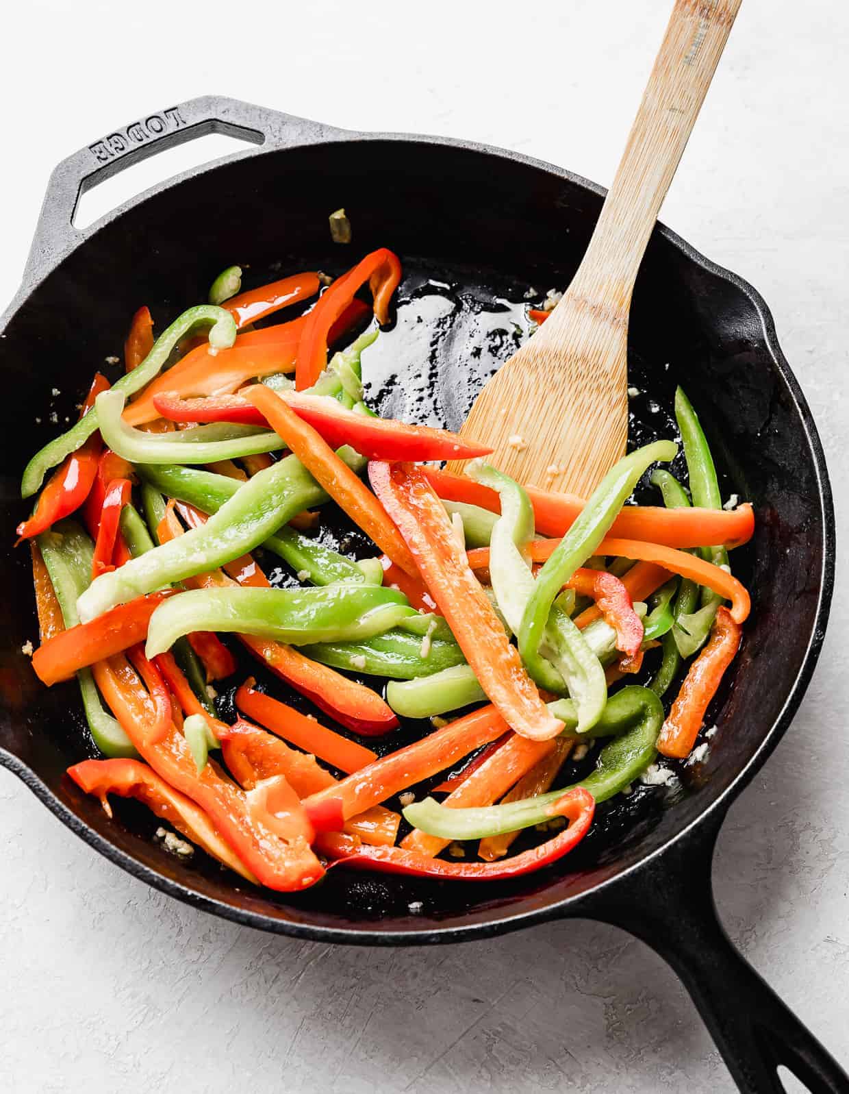 A black skillet with sliced red and green peppers in it.