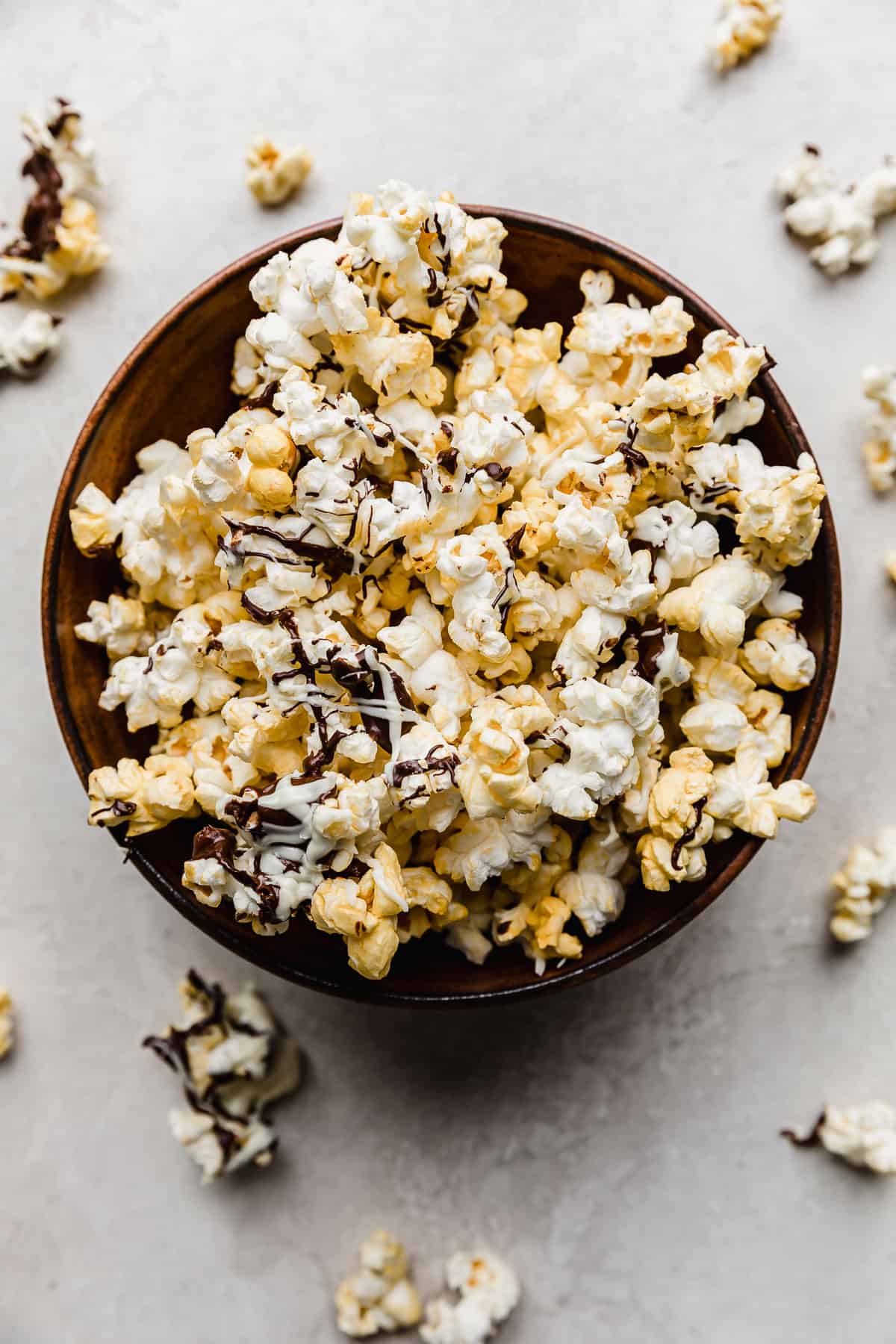 A bowl full of Chocolate Drizzled Popcorn on a gray background.