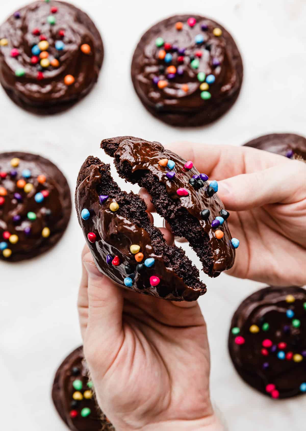 A hand breaking a Crumbl Cosmic Brownie Cookie in half.