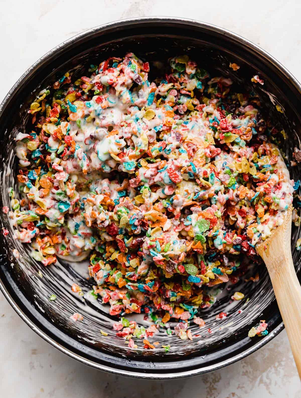 A close up photo of fruity pebbles mixed into melted marshmallows.