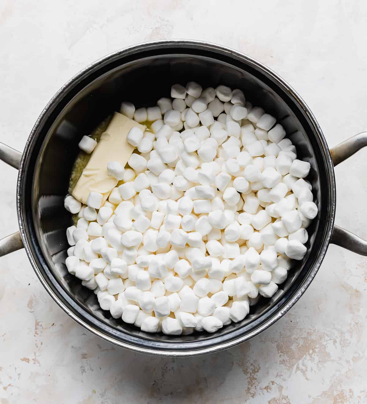A black pot with a cube of butter and mini marshmallows in it.