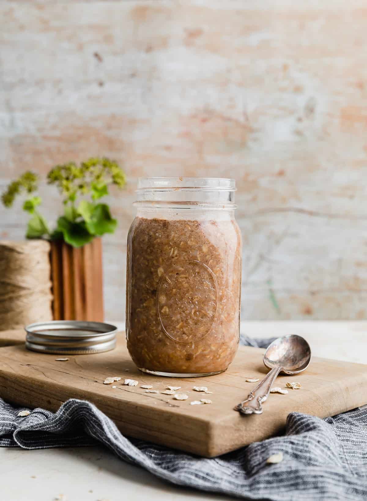 High Protein Overnight Oats in a glass jar on a light brown cutting board.