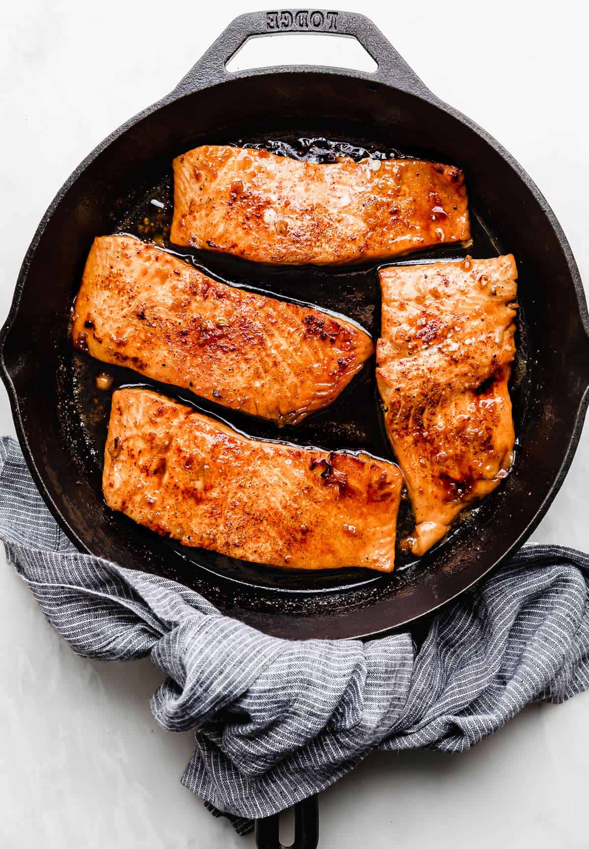 Four Honey Garlic Baked Salmon filets in a cast iron pan.