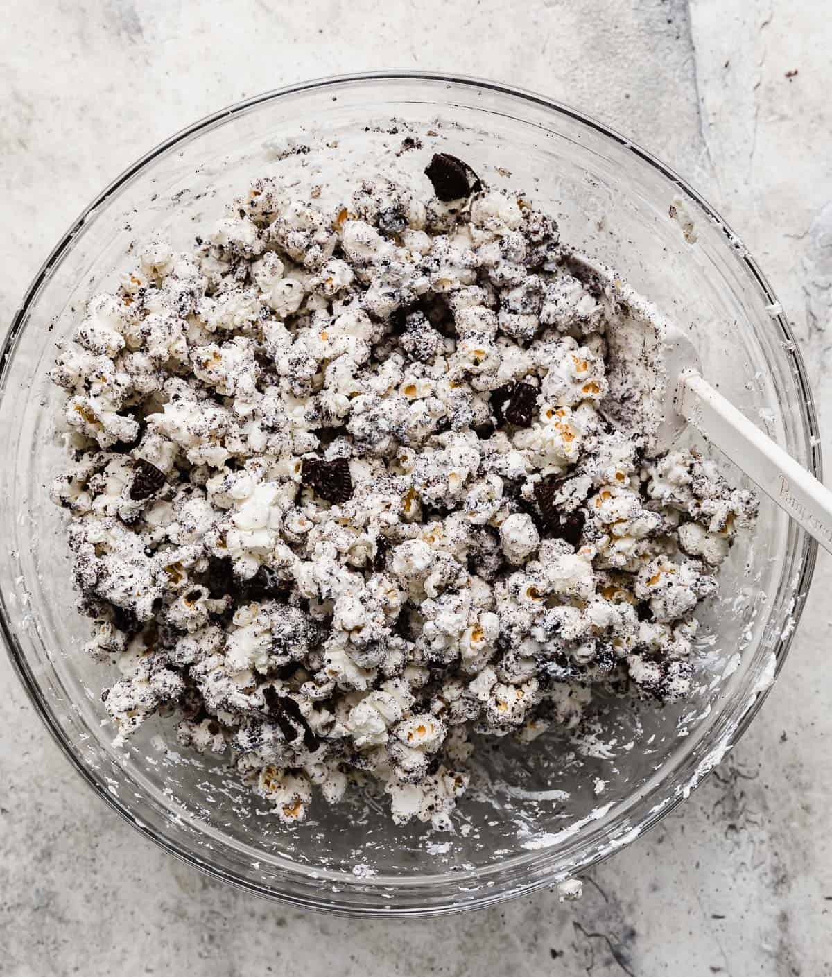 Cookies and cream, Oreo covered popcorn in a large glass bowl on a gray textured background.