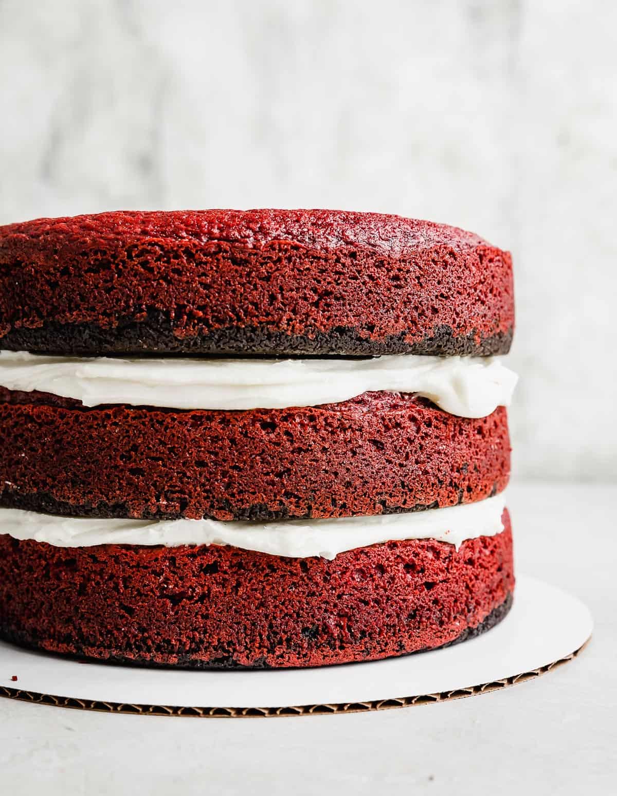 A three tier oreo red velvet cake with cream cheese frosting between each layer.