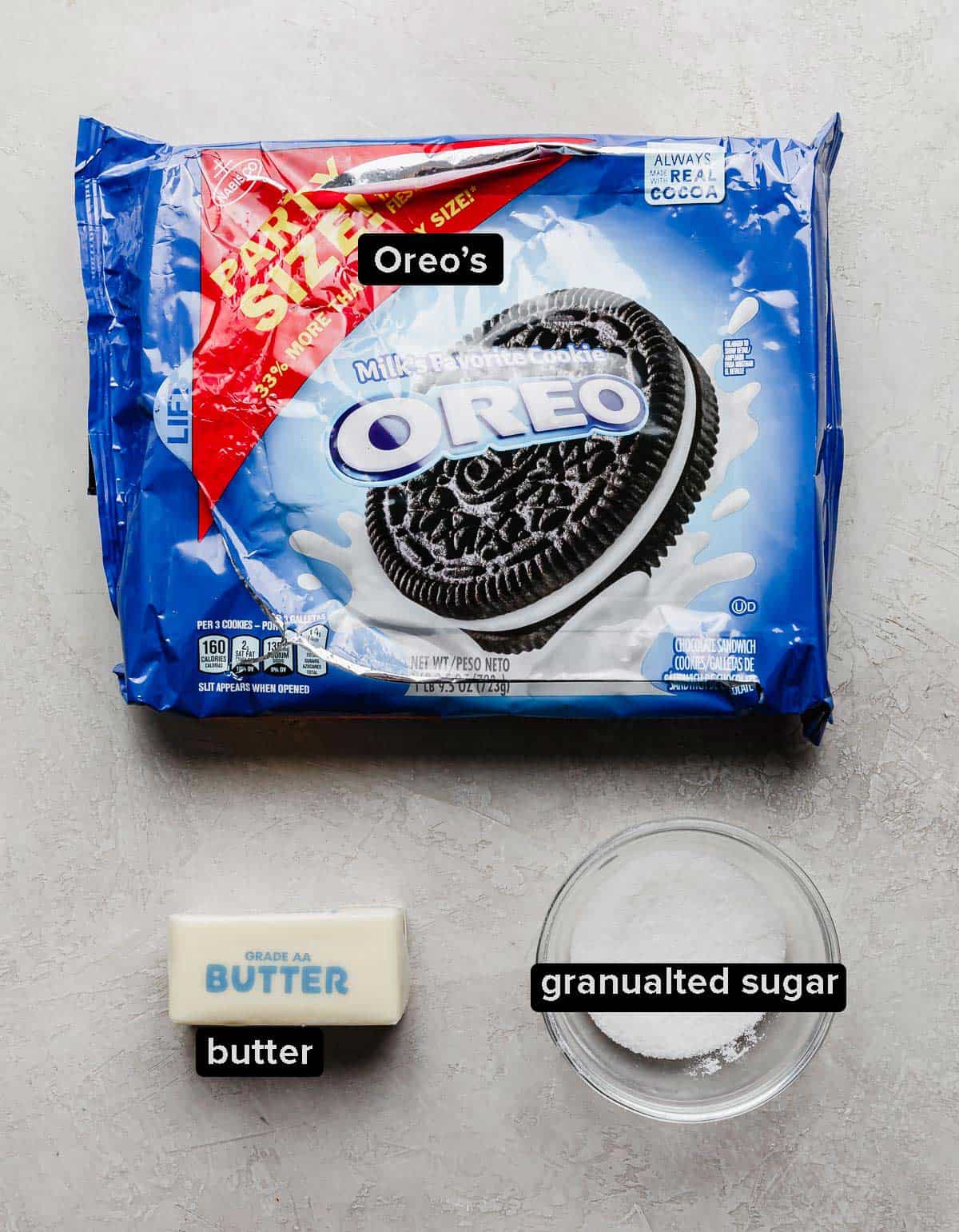 An Oreo package, cube of butter, bowl of sugar on a gray background.