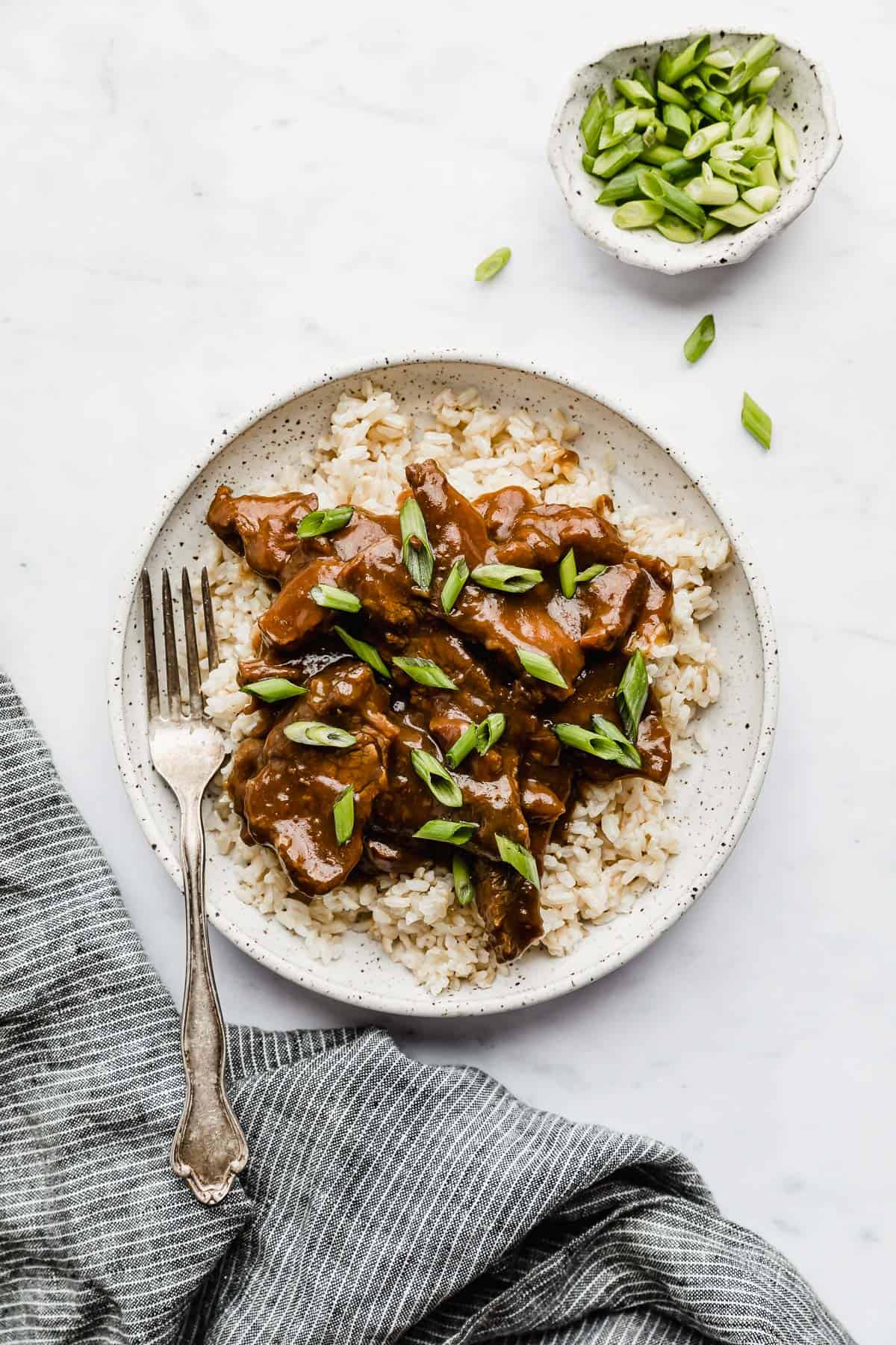 Slow Cooker Mongolian Beef on a plate topped with green onions.