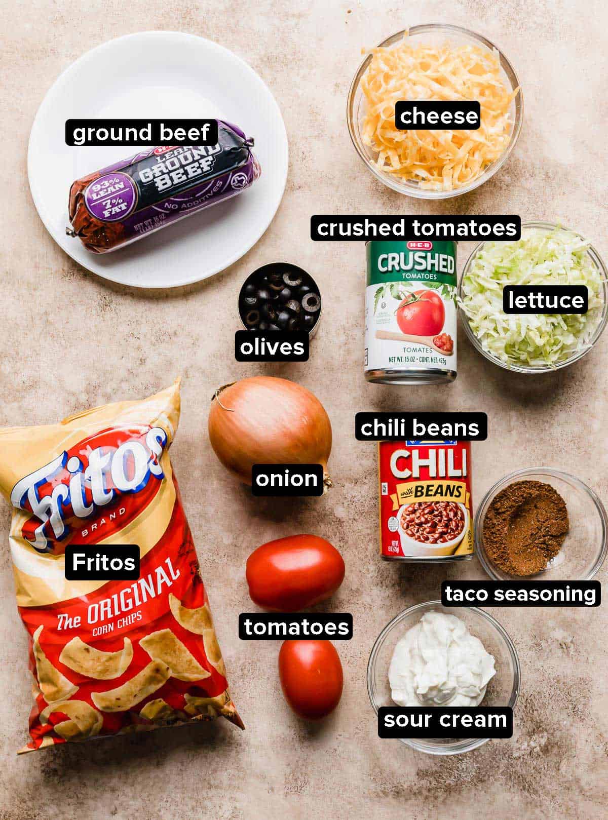 Walking Taco Casserole Recipe ingredients laid out on a beige textured background.