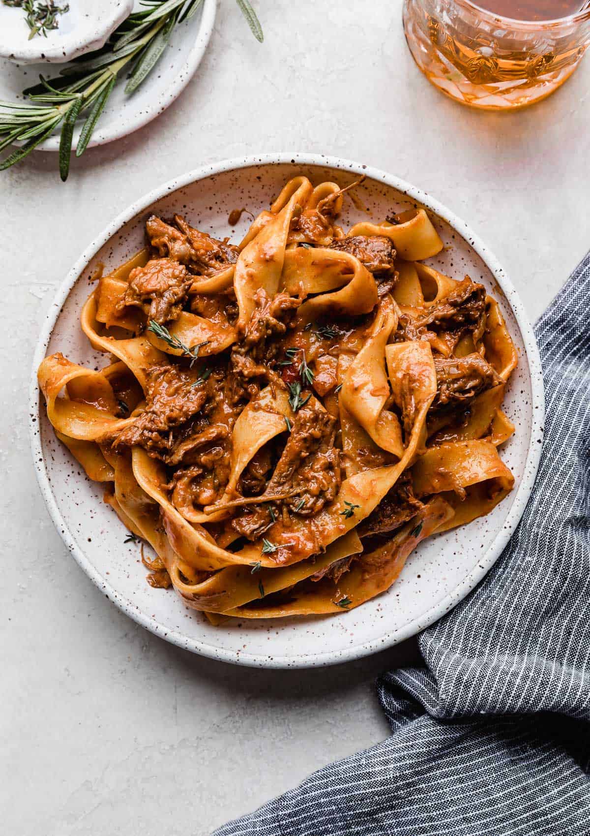 A white plate with homemade beef Ragu with pappardelle noodles on a white background.
