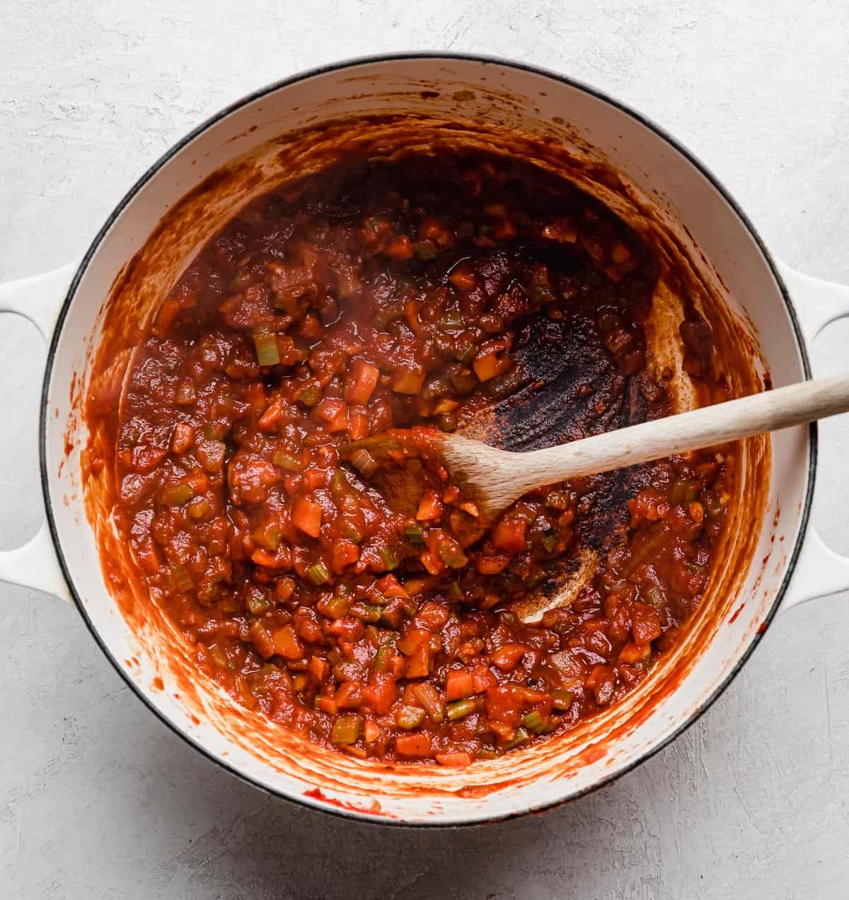 A beef Ragu soffritto and a tomato paste sauce in a large white pot.