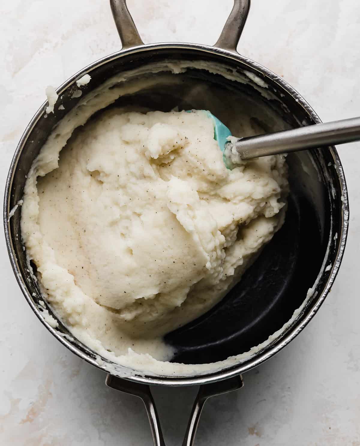 Mashed potatoes in a black pot on a white background.