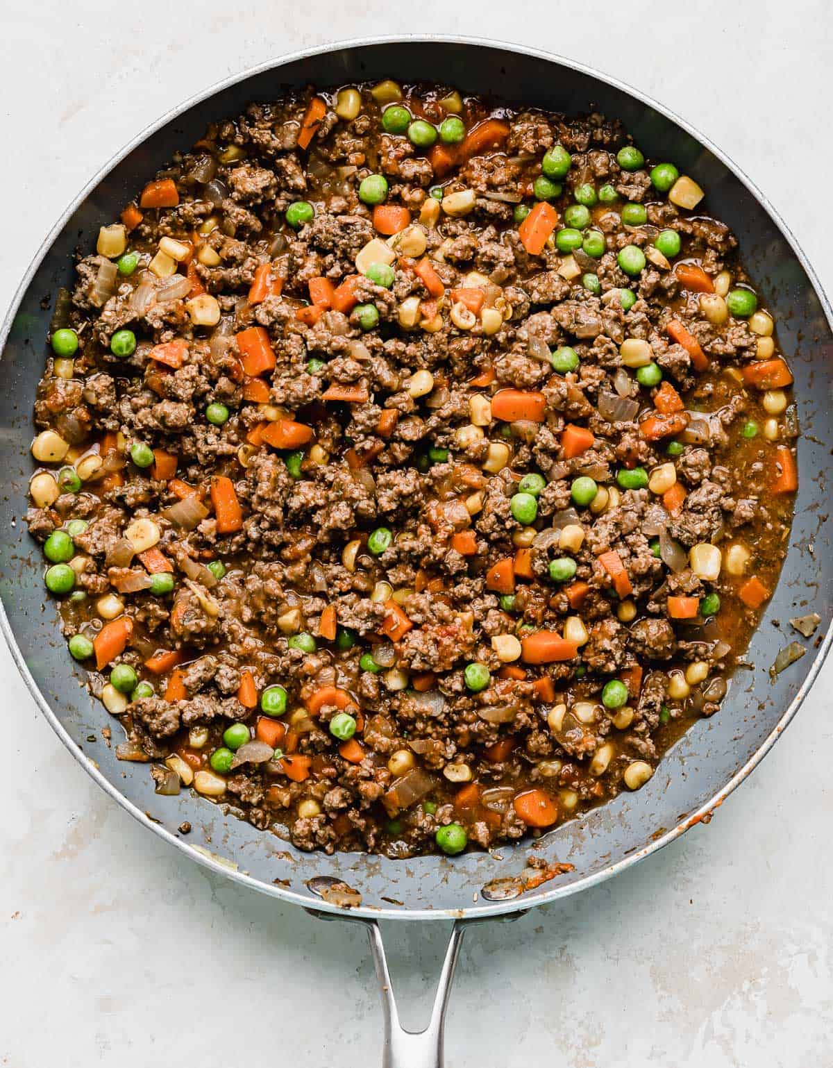 A gray skillet on a white background filled with the best shepherd's pie filling.