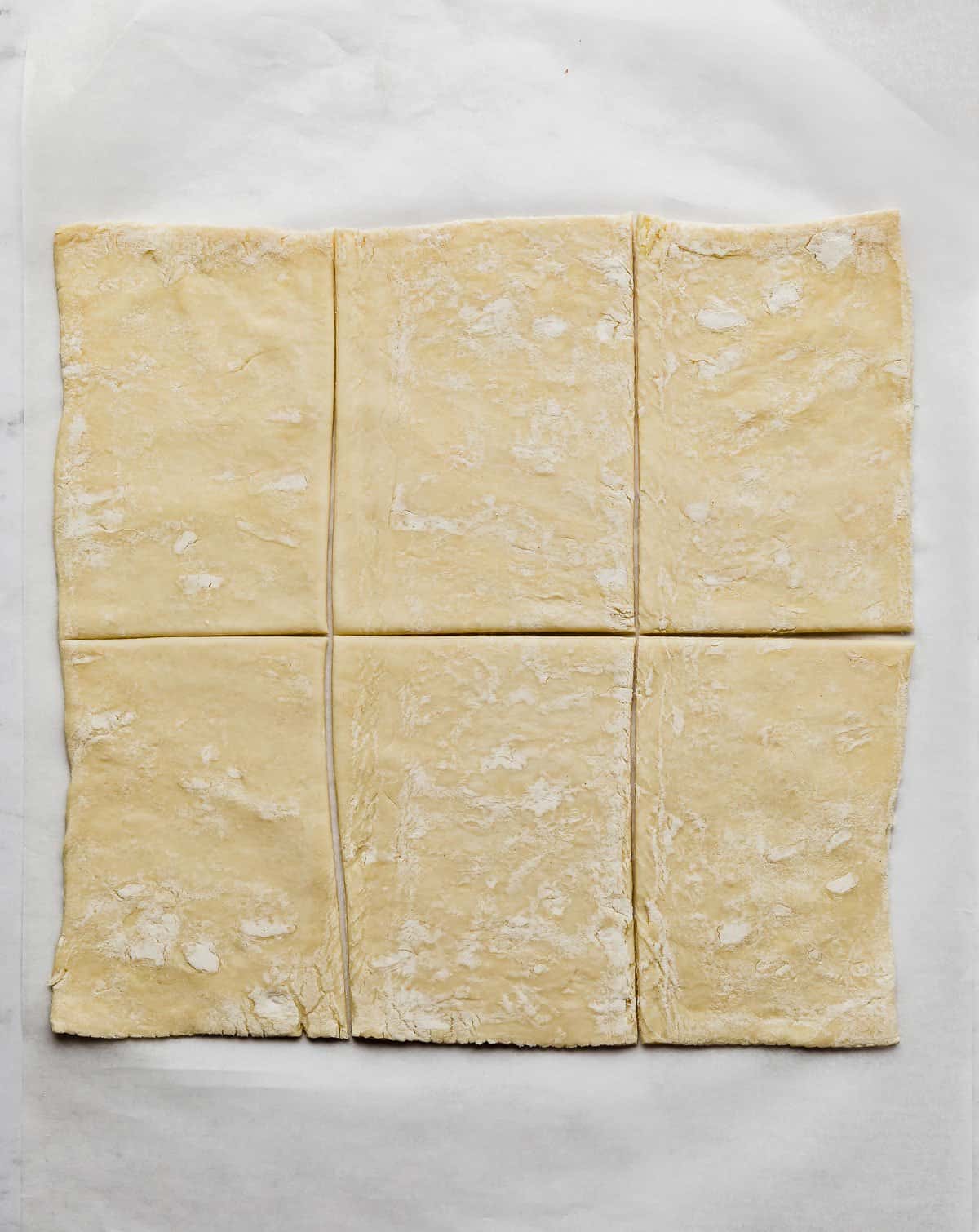 A rectangle of puff pastry cut into 6 rectangular pieces on a white background.