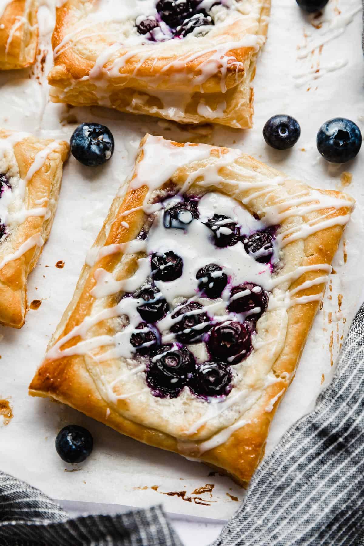 A rectangle blueberry danish with cream cheese filling, topped with a drizzle of white glaze. 