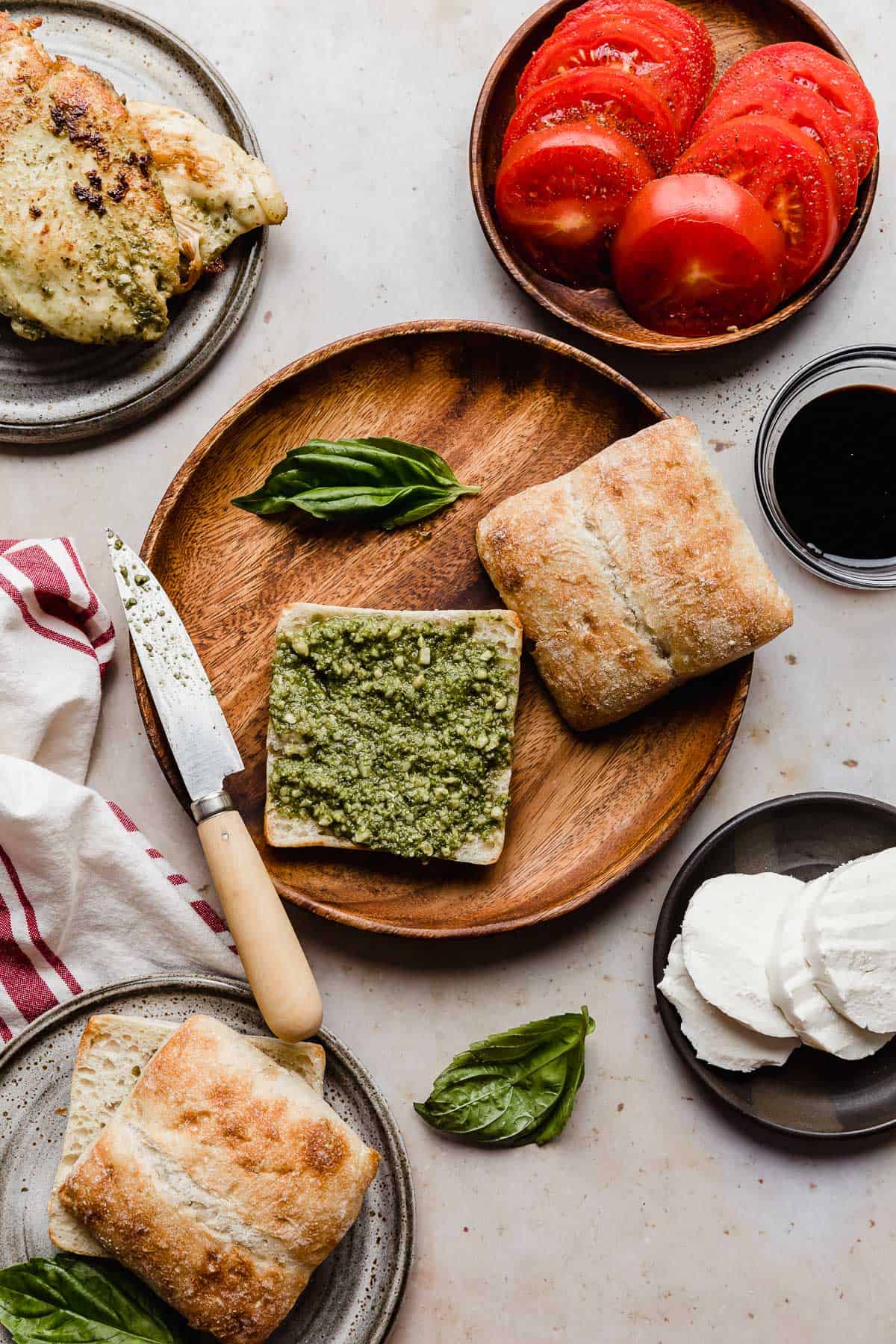 A round wooden plate with a slice of artisan bread on it that has basil pesto smeared overtop.