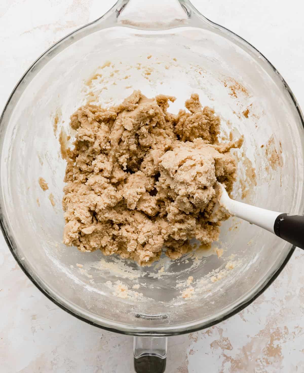 Churro cookie dough in a glass bowl on a white background.