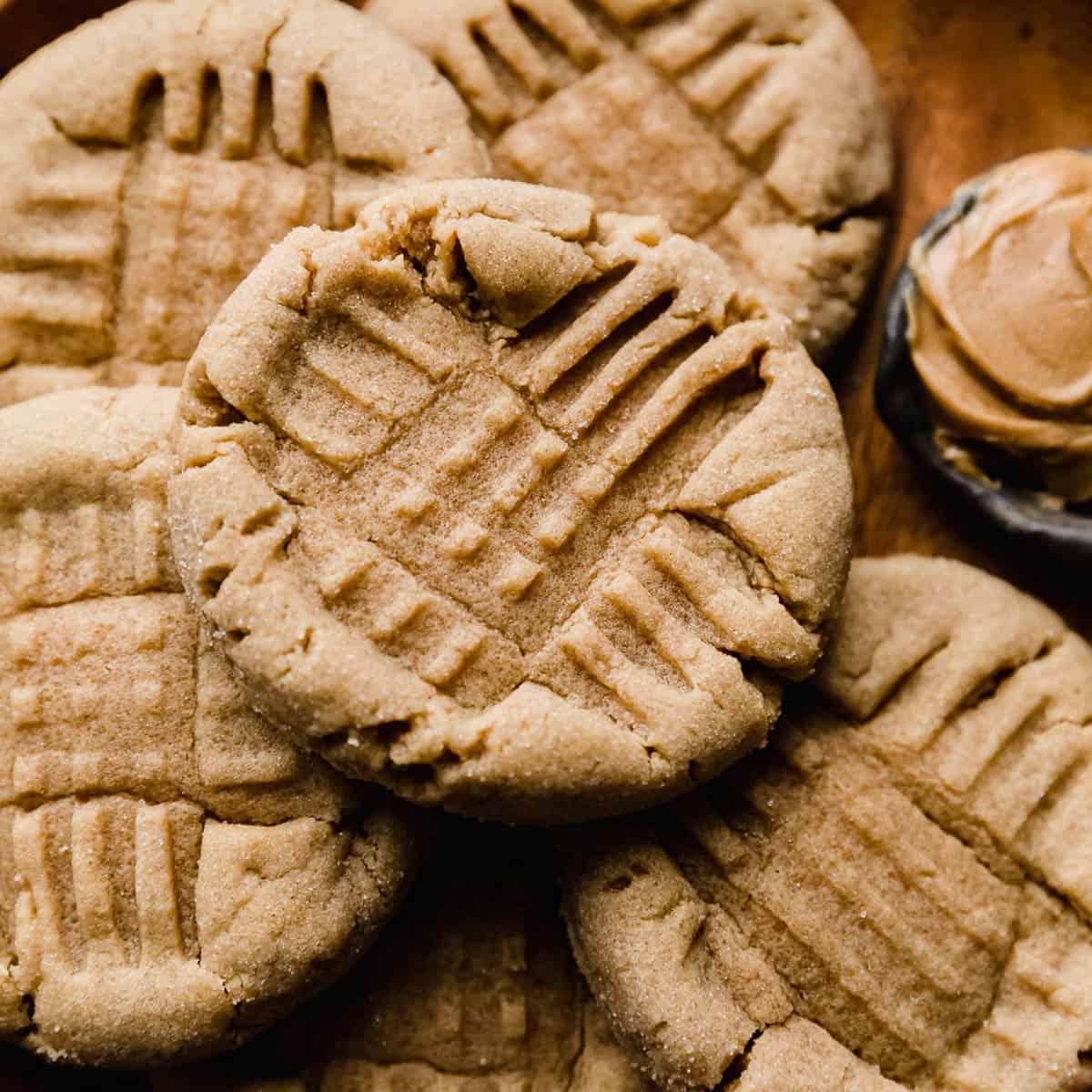 Close up photo of a classic Peanut Butter Cookie with fork tine criss crosses imprinted in the top of the cookie.