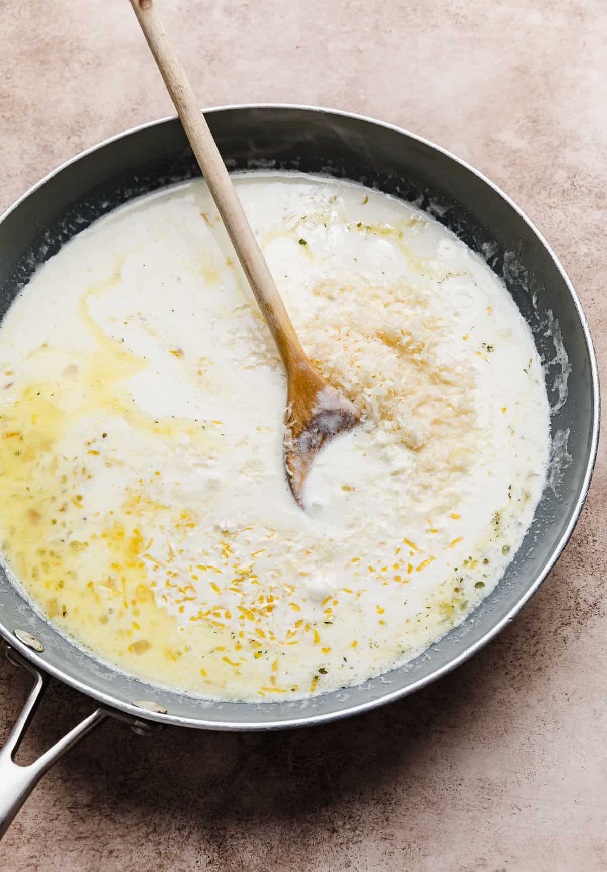 A white sauce in a grey skillet used to make a Creamy Lemon Chicken Pasta recipe.