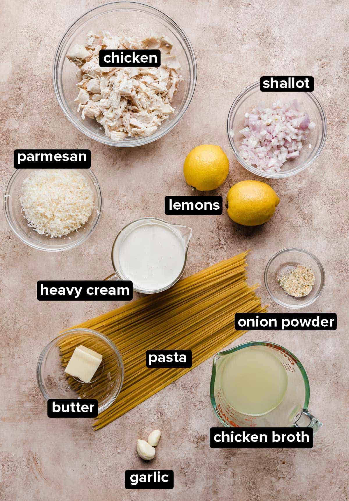 Ingredients used to make Creamy Lemon Chicken Pasta on a beige textured background. 