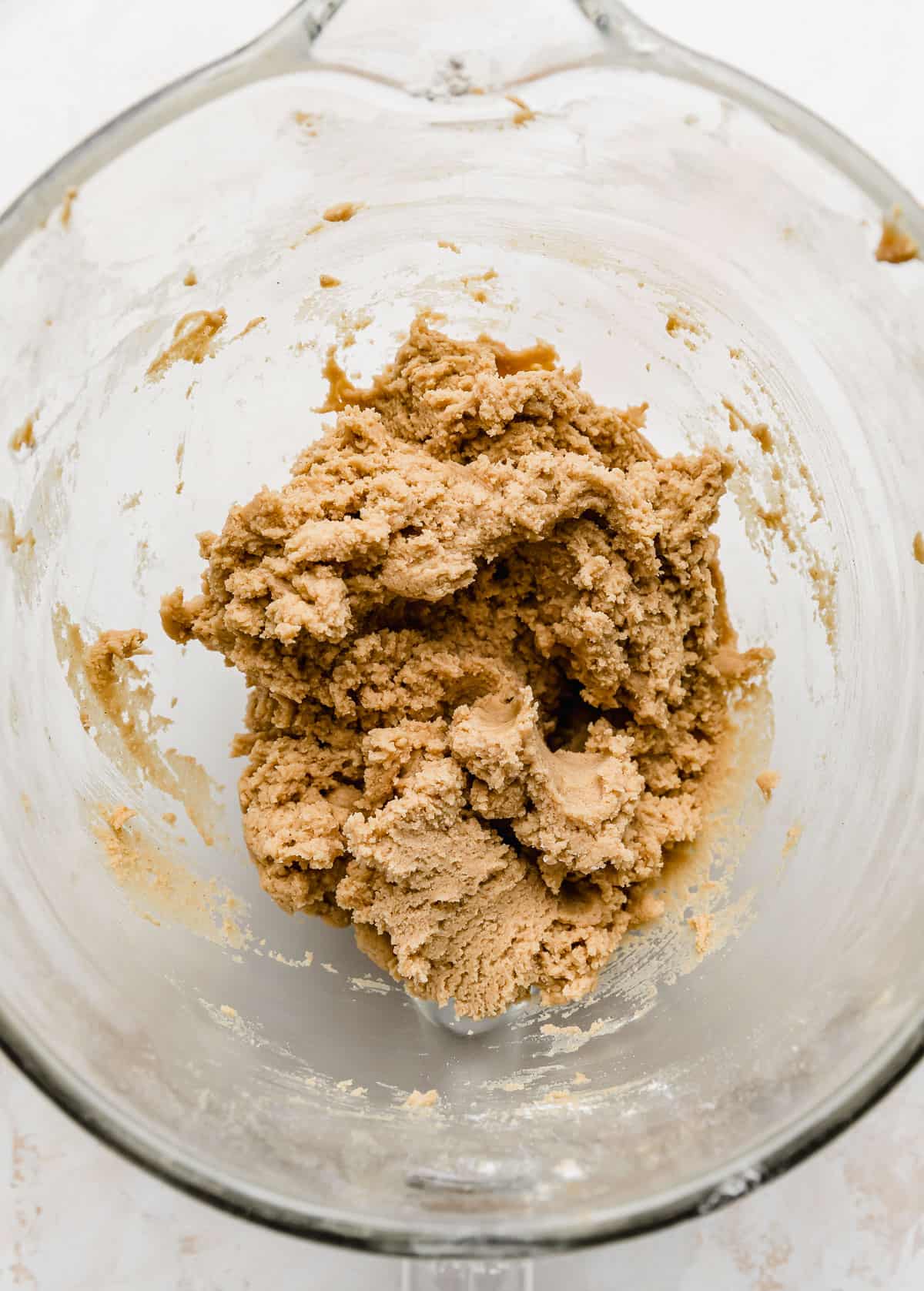 A close up photo of Crumbl Classic Peanut Butter Cookie dough in a glass bowl.