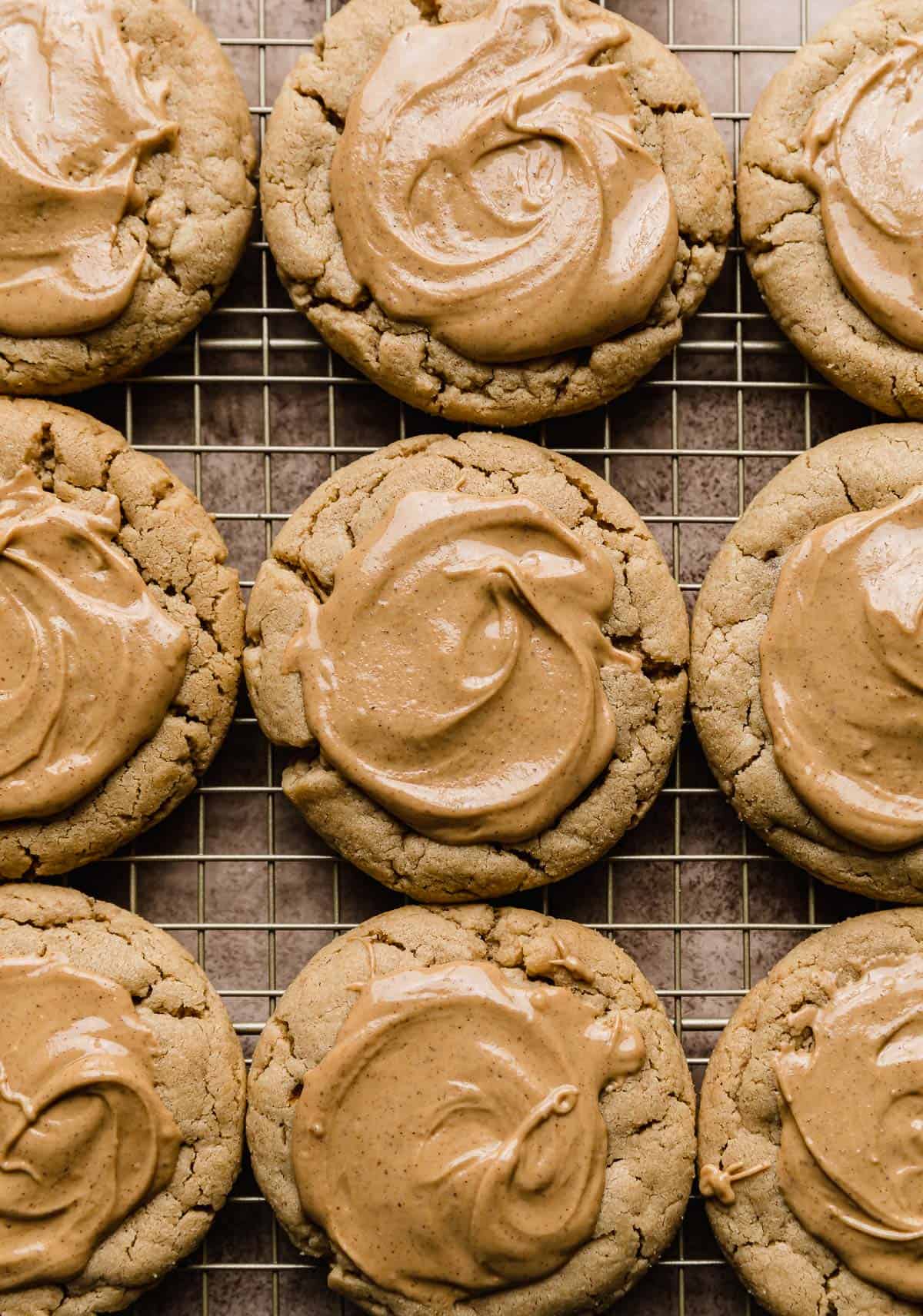 Peanut butter cookies topped with a smooth melted peanut butter topping on a wire rack.