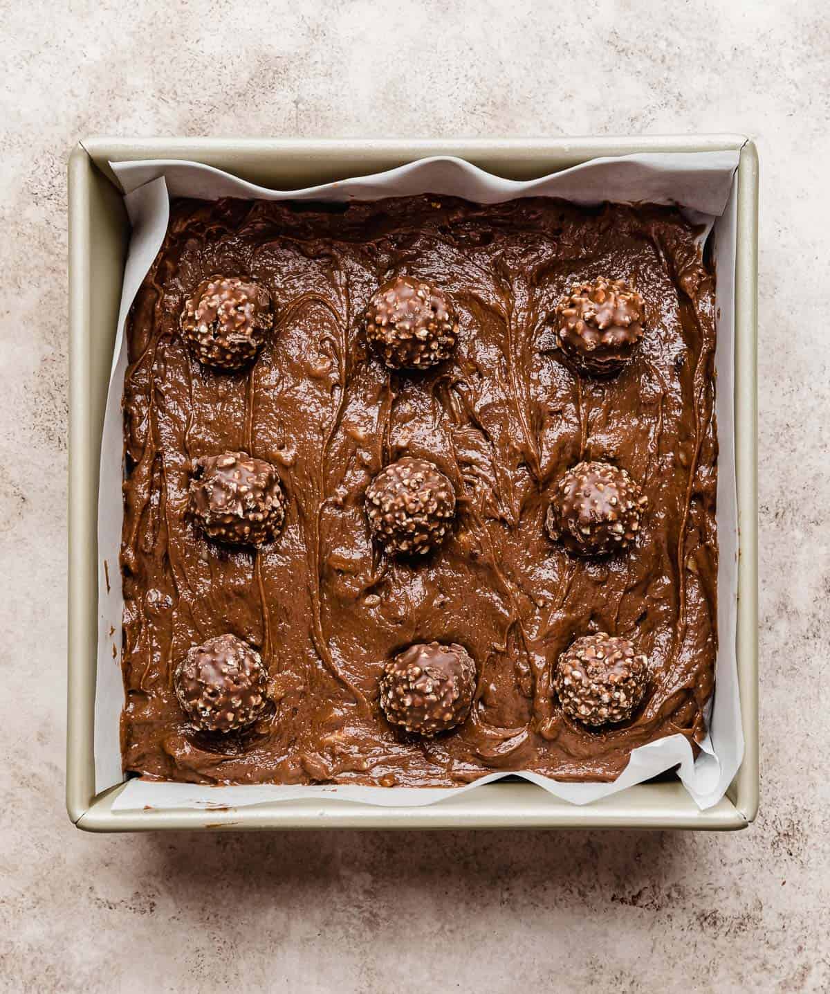 9 Ferrero Rocher's stuck on the top of brownie batter in a square pan.