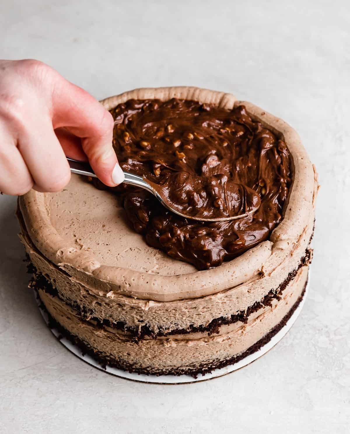 A hazelnut Nutella filling being spread over a chocolate frosting topped cake.