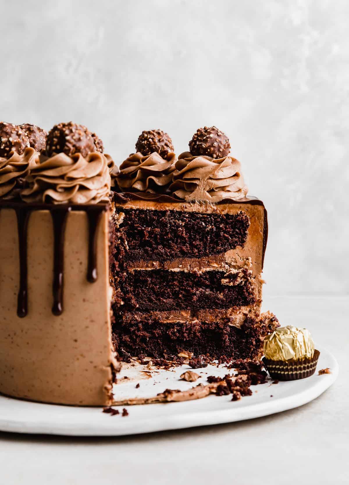 A three layer Ferrero Rocher Cake frosted with chocolate frosting and topped with unwrapped Ferrero Rocher candies.