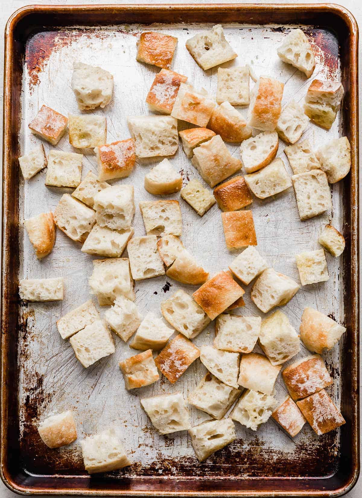 A baking sheet with cubed artisan bread on it.