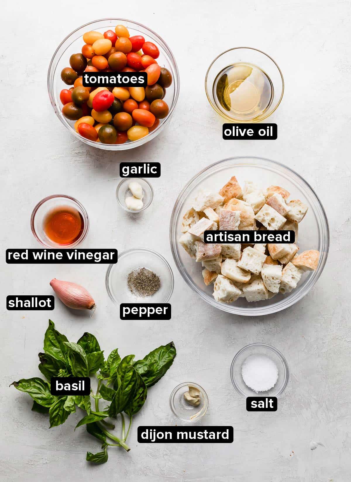 Panzanella Toscana ingredients in glass bowls on a white background.