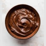 A brown bowl full of swirled Nutella whipped cream on a white background.