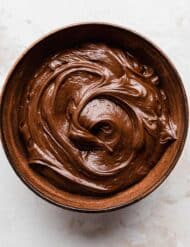 A brown bowl full of swirled Nutella whipped cream on a white background.
