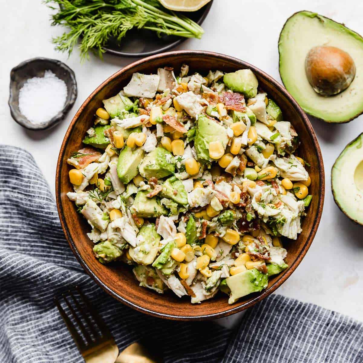 A brown bowl with Avocado Chicken Salad in it on a white background.
