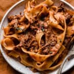 Shredded beef Ragu with pappardelle pasta on a white plate.