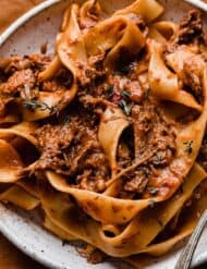 Shredded beef Ragu with pappardelle pasta on a white plate.