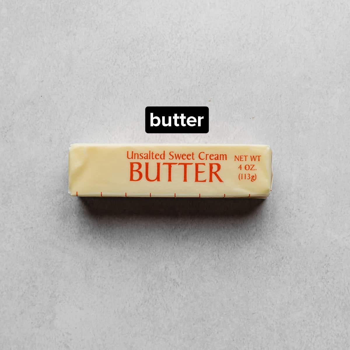 A stick of unsalted butter on a gray background.