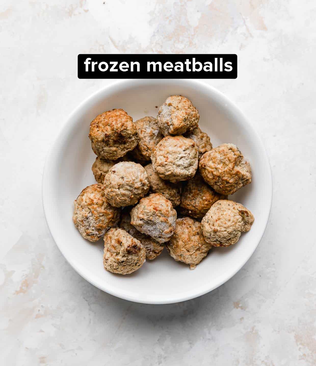 A white bowl with frozen meatballs in it.