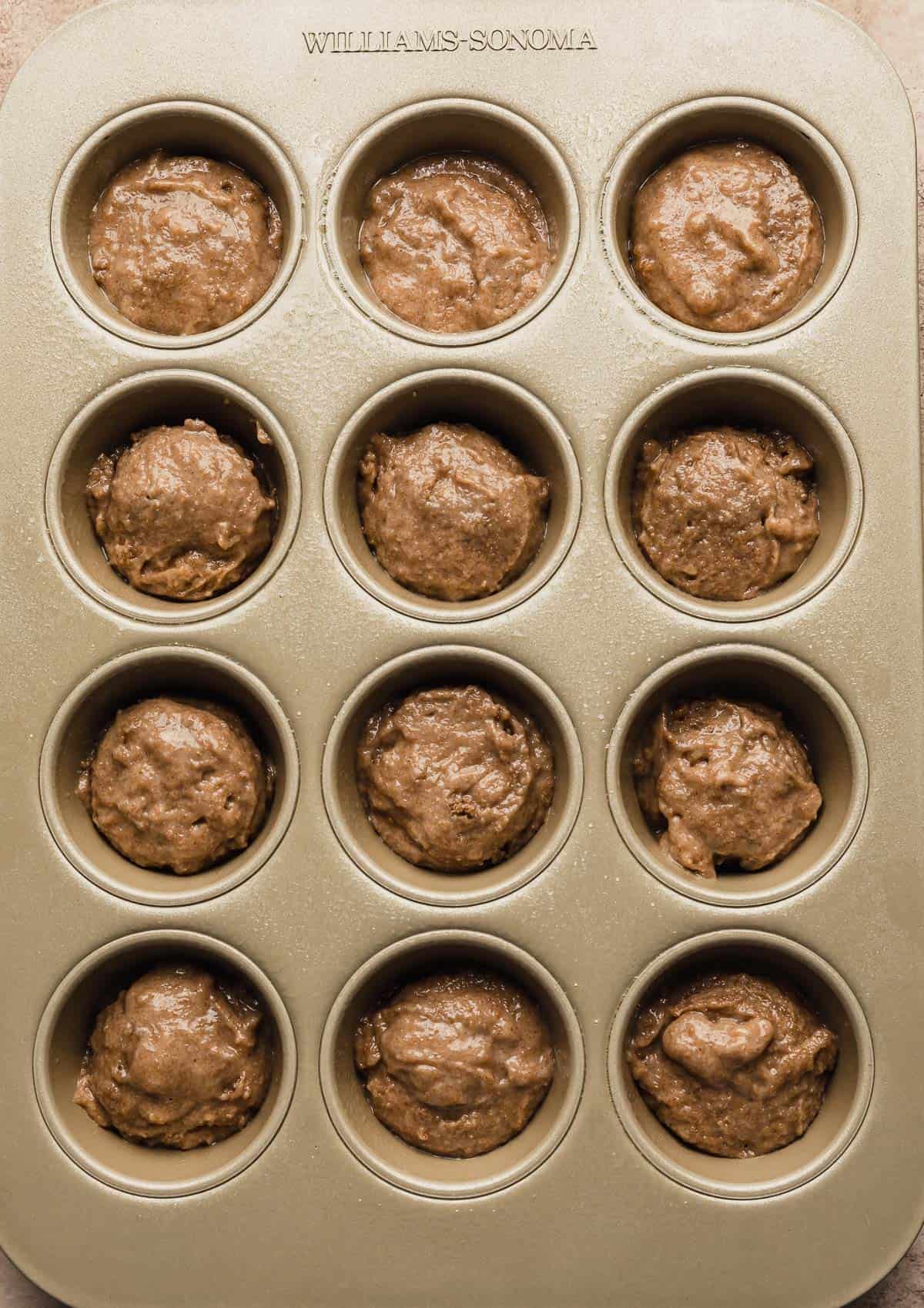 A muffin tin filled with all bran muffin batter.