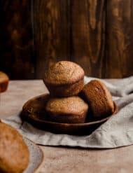All Bran Muffins with buttermilk stacked on a small wooden plate against a wooden background.