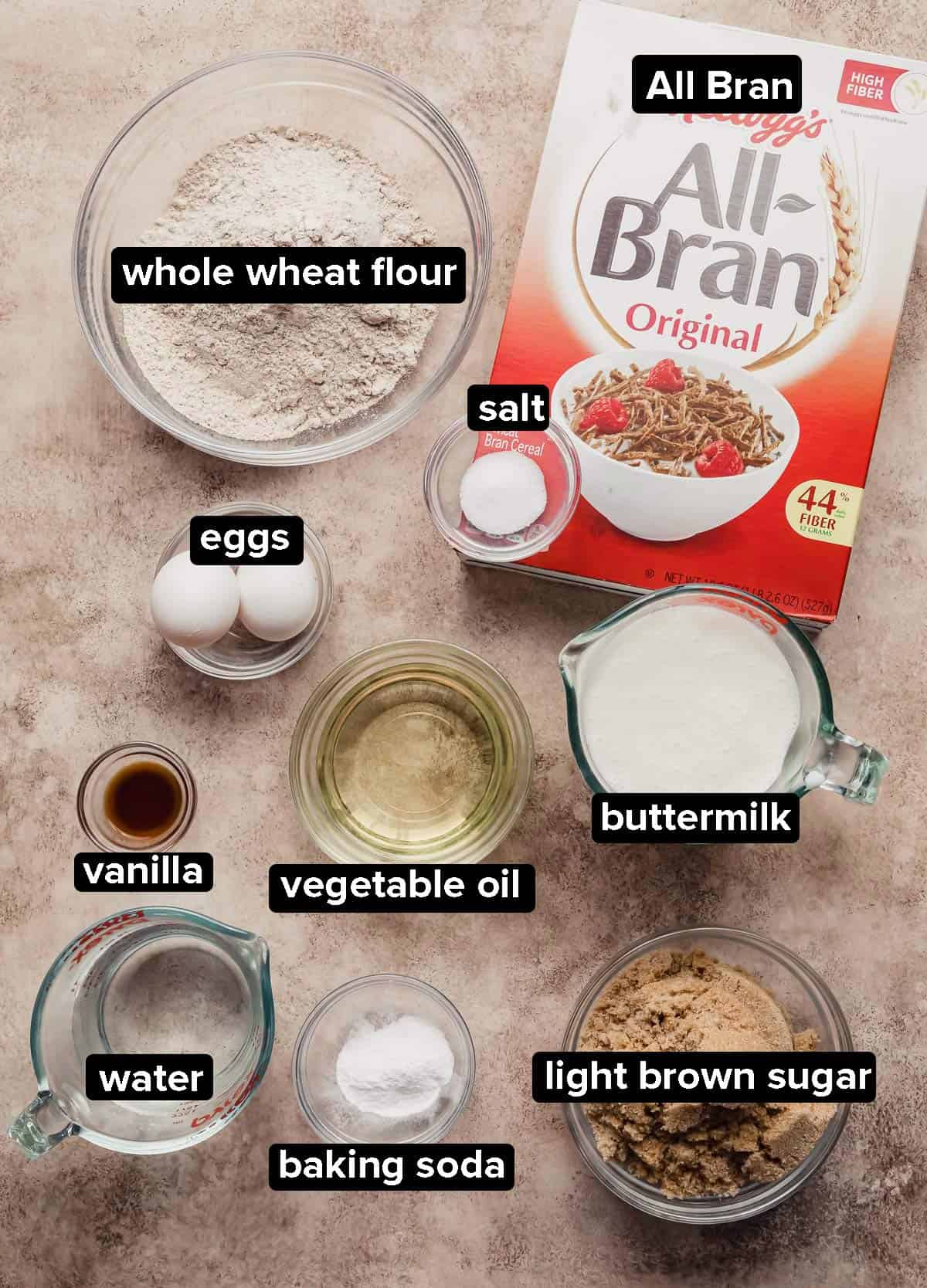 All Bran Muffins ingredients portioned into glass bowls on a beige textured background.